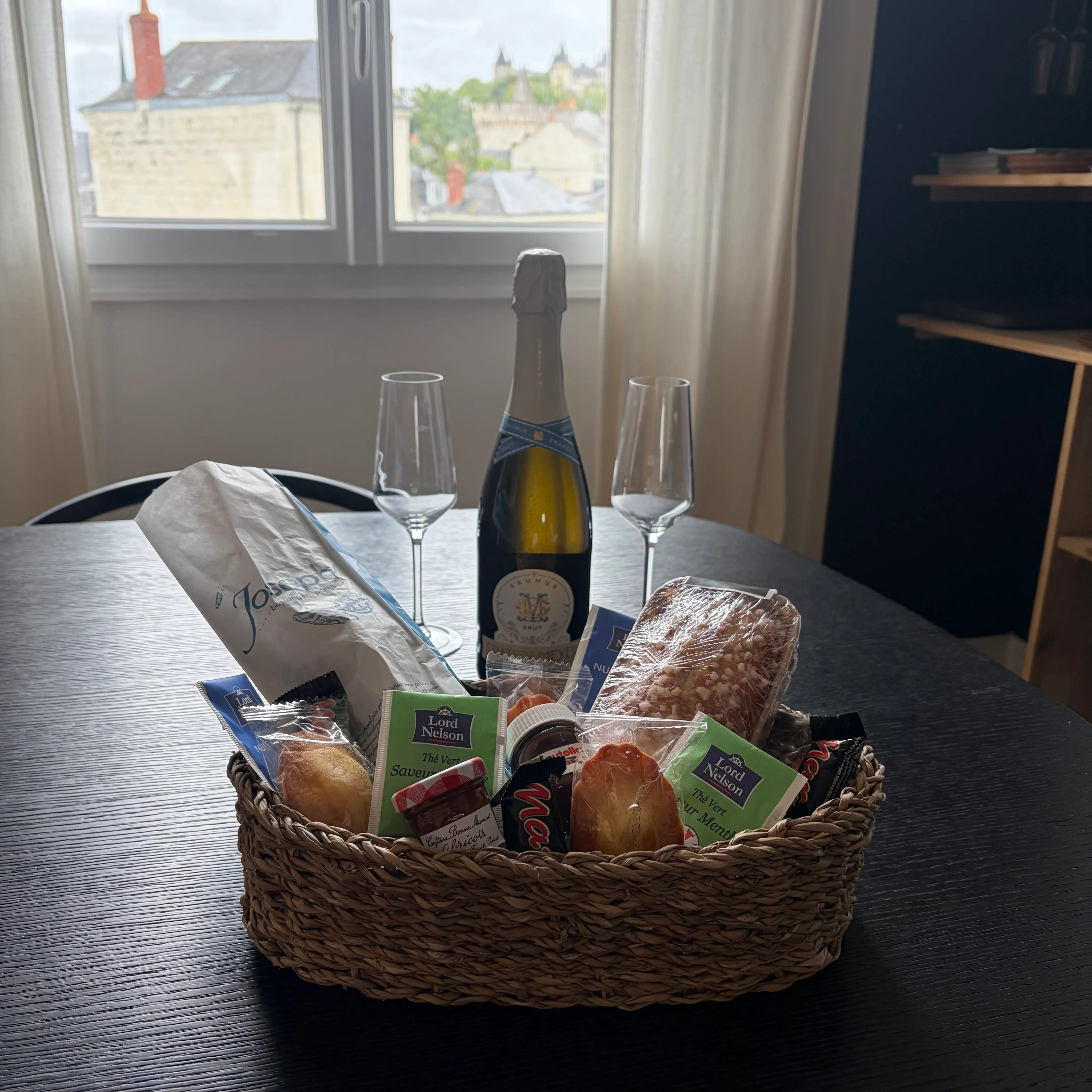 Panier de gourmandises et bouteille disposés sur la table du Belvédère