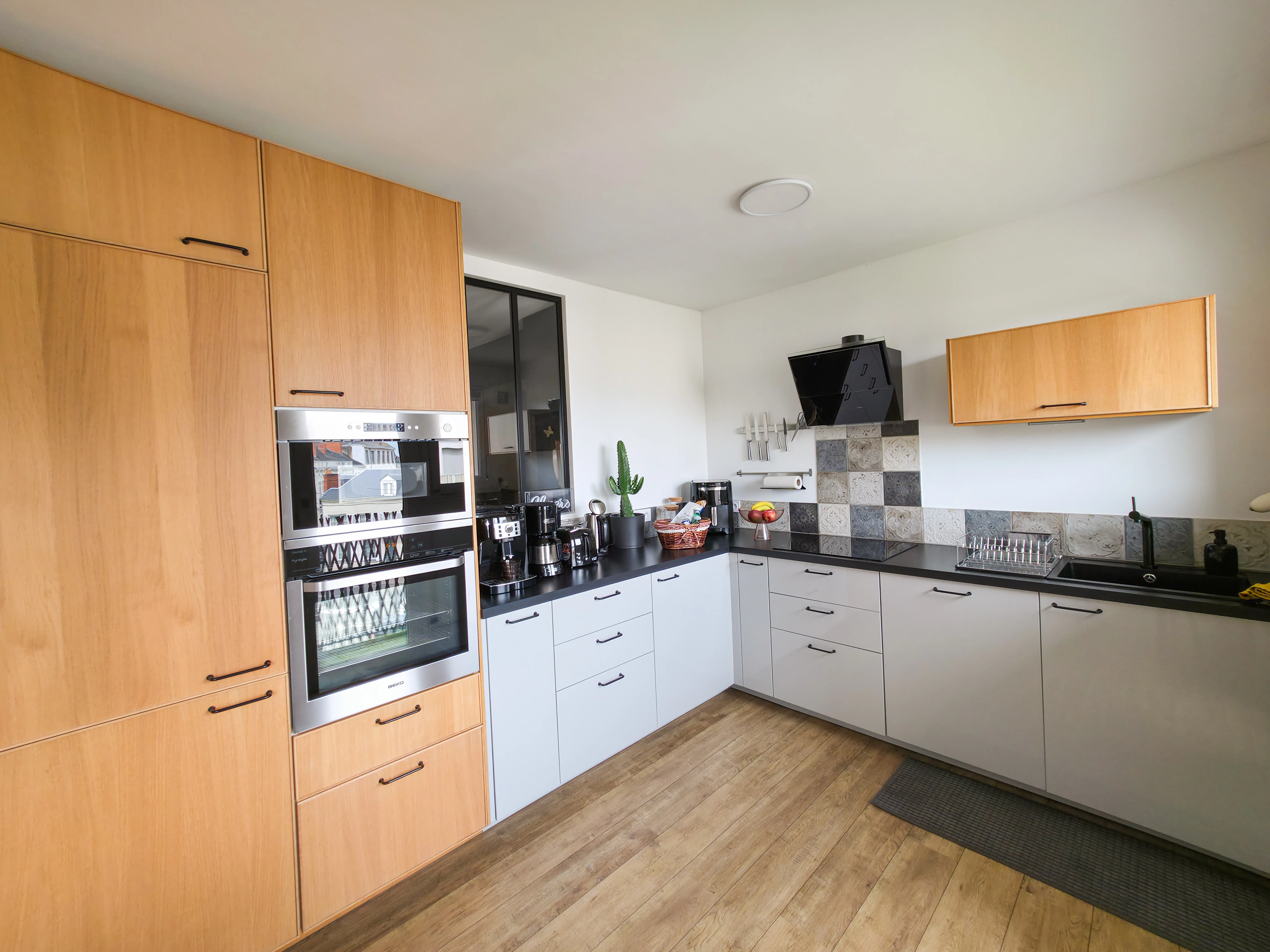 Cuisine du Belvédère avec façades en bois, four et plan de travail noir