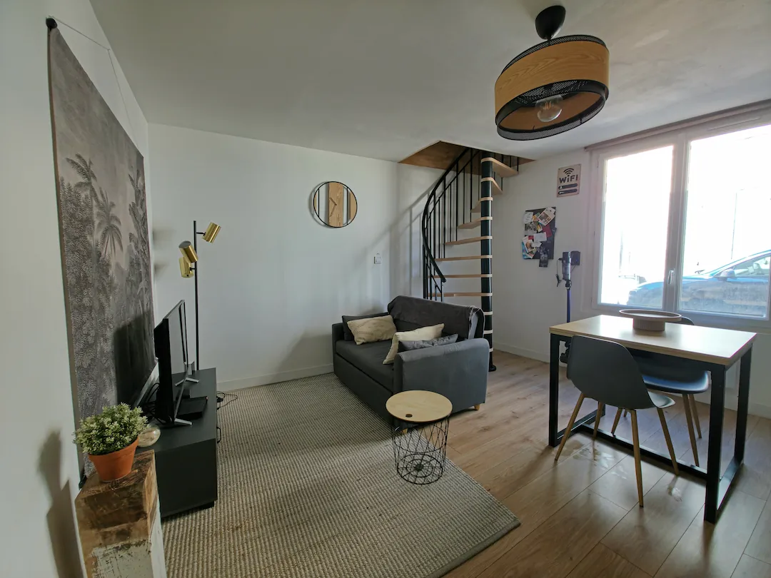 Salon du Loft avec canapé, télévision et espace repas près de la fenêtre